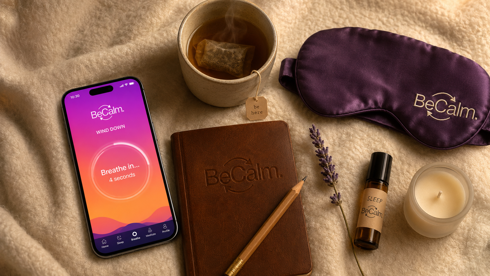BeCalm pre-sleep bedside ritual flat-lay — phone tilted showing the WIND DOWN breathing screen with the master BeCalm wordmark + arrows logo, stoneware mug of herbal tea, plum silk eye mask with the wordmark embroidered at the corner, leather journal with the wordmark debossed on the cover, amber-glass SLEEP oil roller, frosted candle, dried lavender, all on soft cream wool blanket under warm asymmetric tungsten light