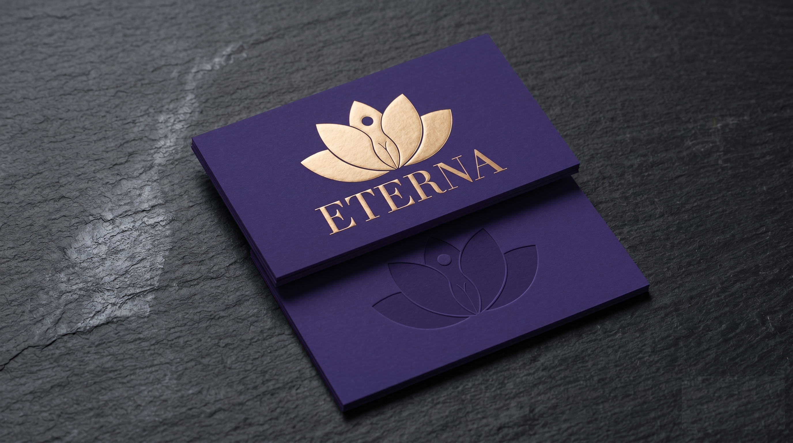 ETERNA royal-purple business cards stacked at 30 degrees with gold-foil monogram